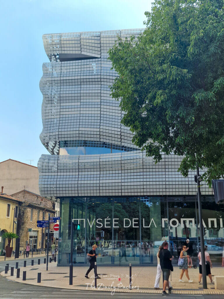 Façade moderne en verre du Musée de la Romanité de Nîmes, reflétant l'esprit ancien et nouveau de la ville.