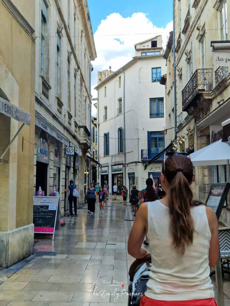 Flânerie dans les rues commerçantes de Nîmes, avec ses façades en pierre et ses estivants.