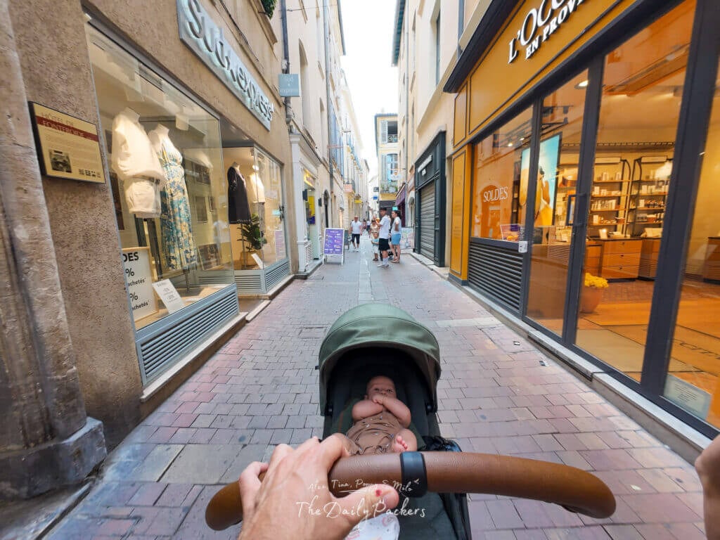 Promenade dans une rue piétonne commerçante de Nîmes avec un bébé dans une poussette
