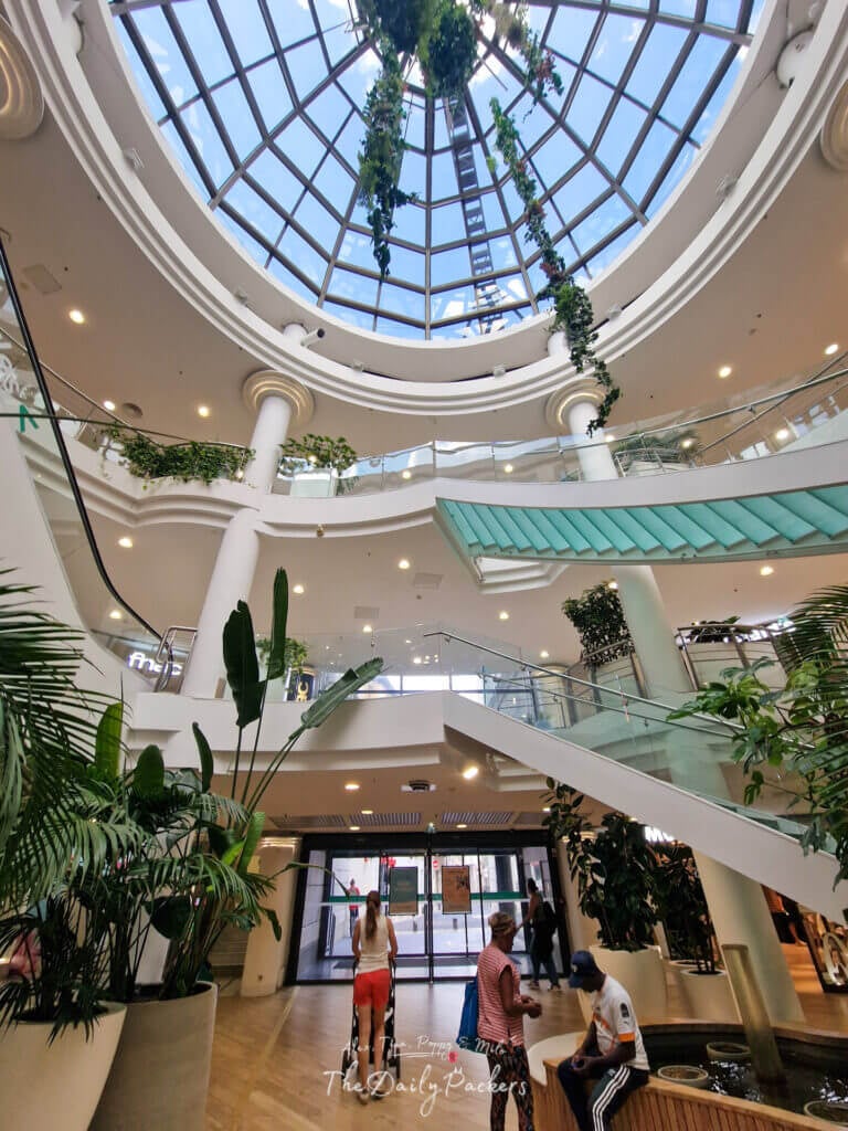 Intérieur lumineux des Halles de Nîmes avec un plafond en dôme de verre et des plantes suspendues