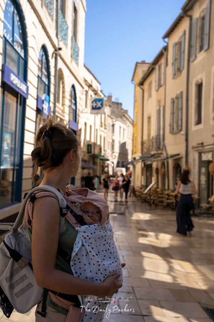 Mère portant un bébé dans la vieille ville de Nîmes, marchant dans une charmante rue commerçante