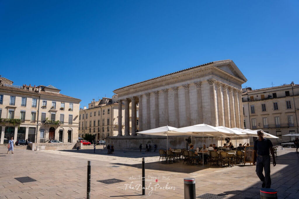 Le temple romain Maison Carrée à Nîmes avec une terrasse de café aménagée sous des parasols