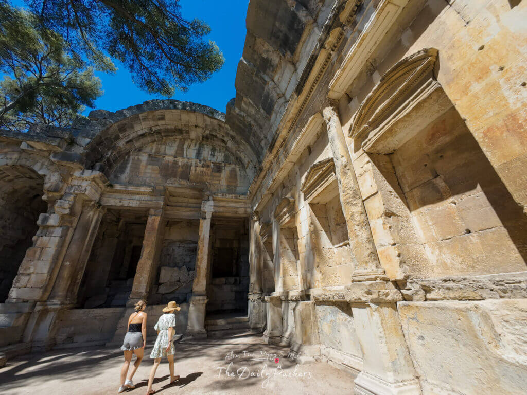 Deux femmes marchant à l'intérieur du temple de Diane à Nîmes, admirant l'architecture romaine partiellement préservée.