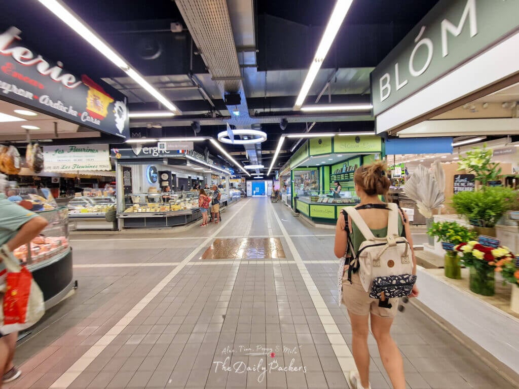 A l'intérieur des Halles de Nîmes, un marché couvert très animé avec des stands de nourriture et des habitants qui font du shopping.
