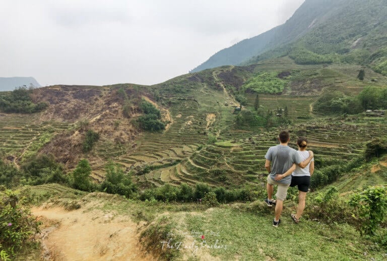Couple standing arm in arm gazing over the lush green terraced hills of Sapa during a Sapa Trekking