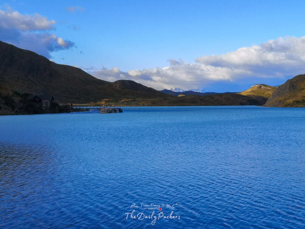 View of the Pudeto pier and surrounding hills reflected in the blue waters of Torres del Paine.