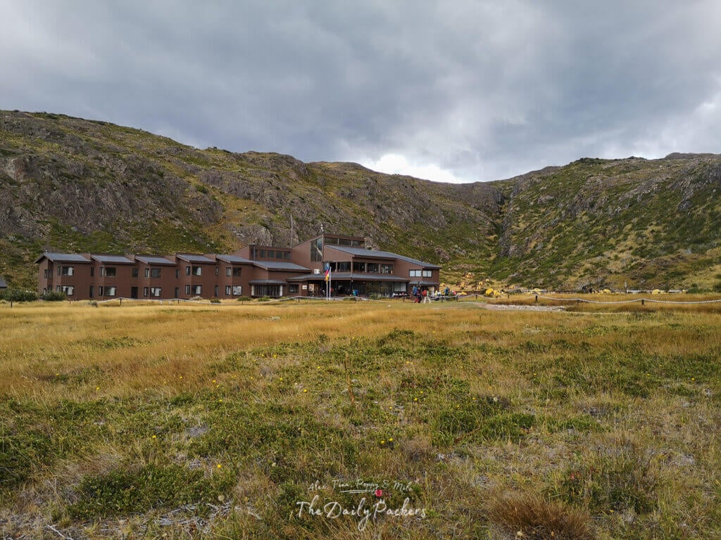 Wide view of Paine Grande Lodge surrounded by grassy plains and mountains in Torres del Paine.
