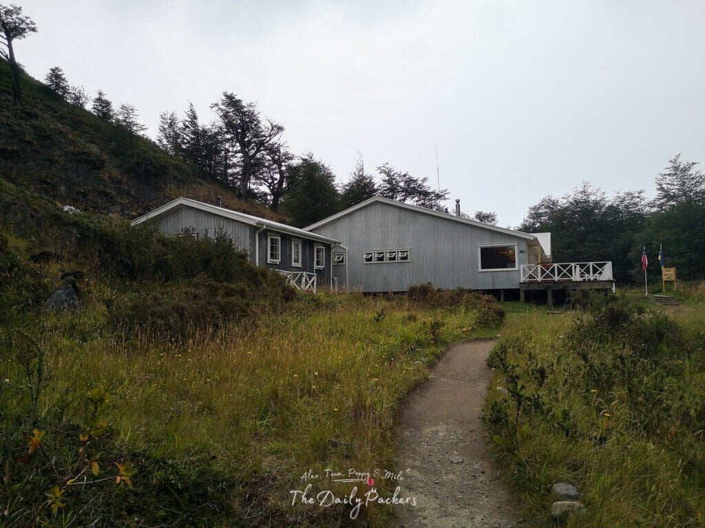 Exterior view of Refugio Grey in Torres del Paine, surrounded by grassy hills and forest.