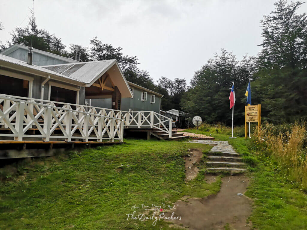 Entrance area of Refugio Grey with Chilean and Magallanes flags and a wooden sign.