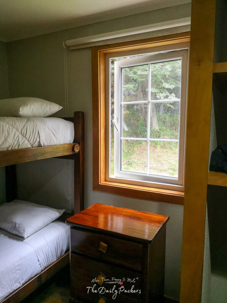 Close-up of a bunk bed next to a window inside Refugio Grey, with a nightstand underneath