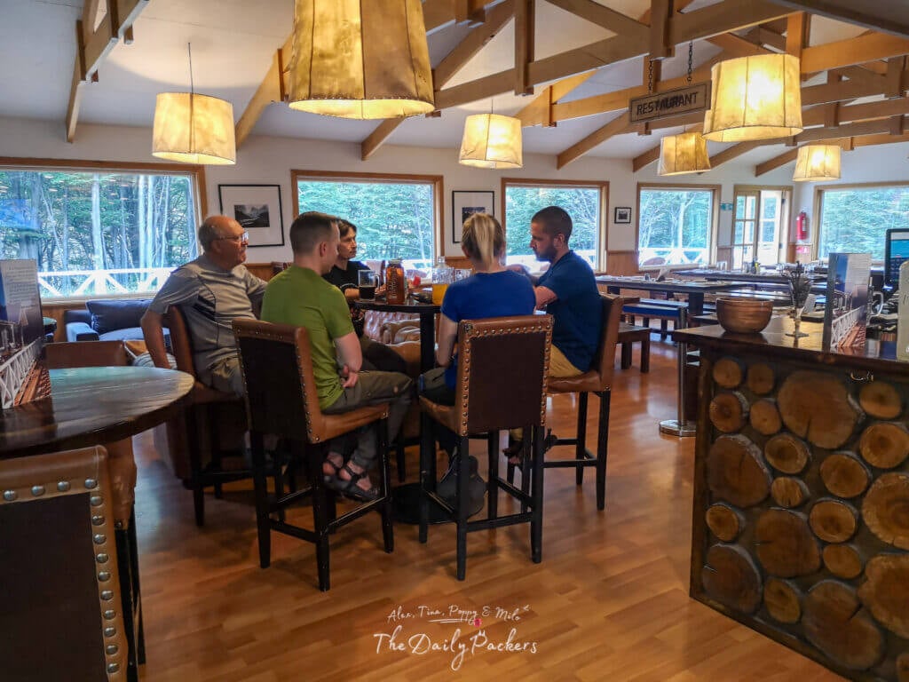 Group of hikers sitting and chatting inside the cozy wooden dining area of Refugio Grey in Torres del Paine National Park.