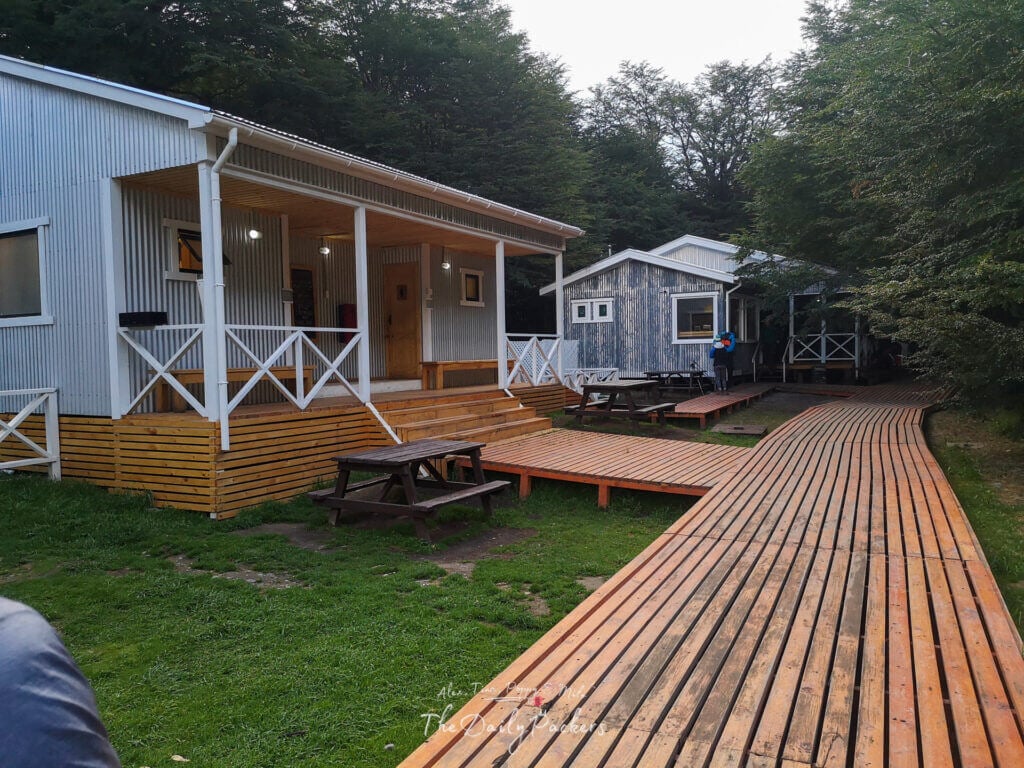 Wooden boardwalk leading to the shower and facilities area at Refugio Grey, surrounded by forest.