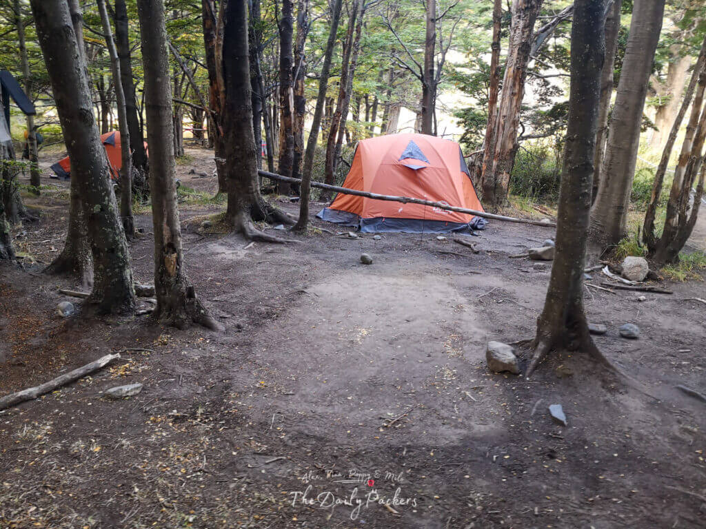 Orange camping tent set up among trees in the camping area of Refugio Grey.