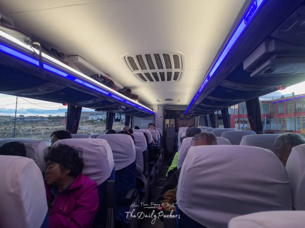 Interior of a long‑distance coach to Puerto Natales, passengers seated under blue aisle lighting.