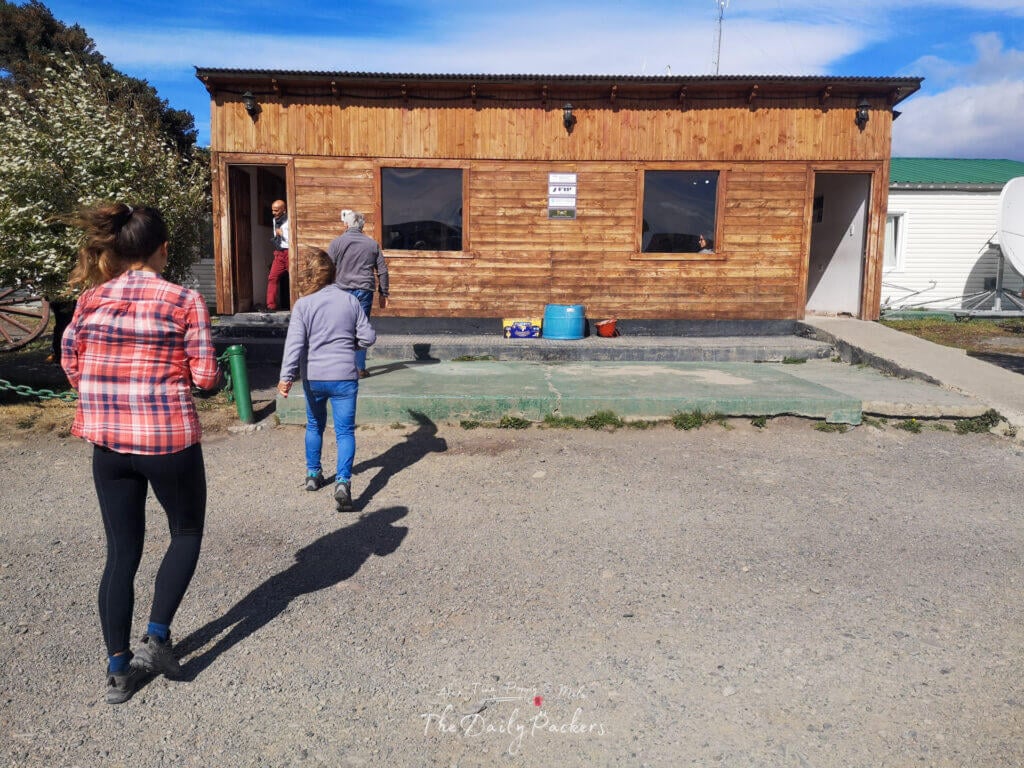 Small wooden building at the Argentina border post with travelers walking toward immigration.