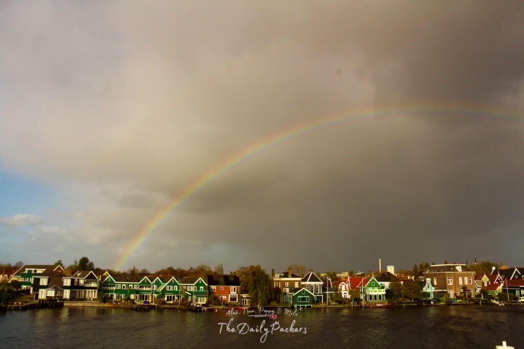 Un arc-en-ciel traversant un ciel lunatique au-dessus des maisons vertes et colorées de Zaanse Schans.
