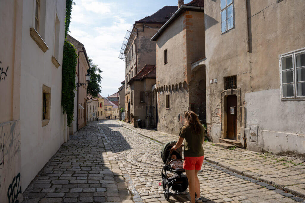 Quiet cobblestone street in Bratislava’s old town with historic houses and a woman pushing a stroller.