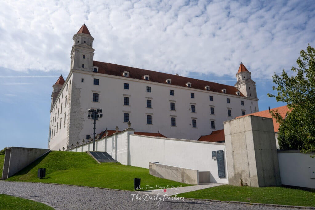 Bratislava Castle with its four corner towers and white façade seen from below.