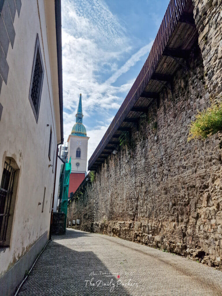Medieval stone city wall with wooden walkway and St. Martin’s Cathedral tower in the background