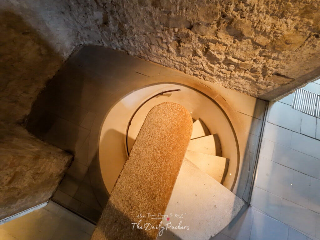 Narrow spiral stone staircase inside Bratislava Castle with rustic stone walls.
