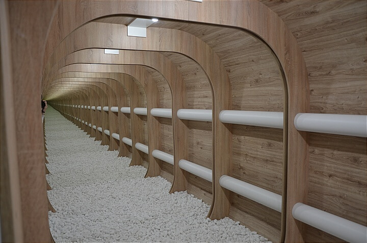 Futuristic infinity mirror installation at Gallery Multium in Bratislava with wooden arches and white stones.