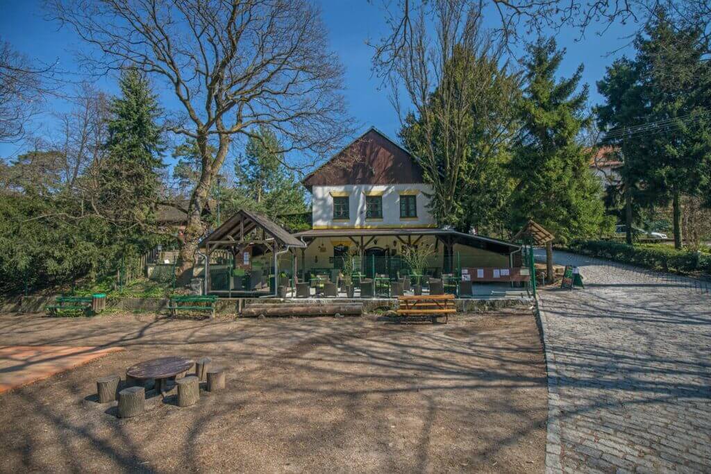 Koliba Kamzík in Bratislava’s Mountain Park with outdoor seating surrounded by trees and cobblestone paths.