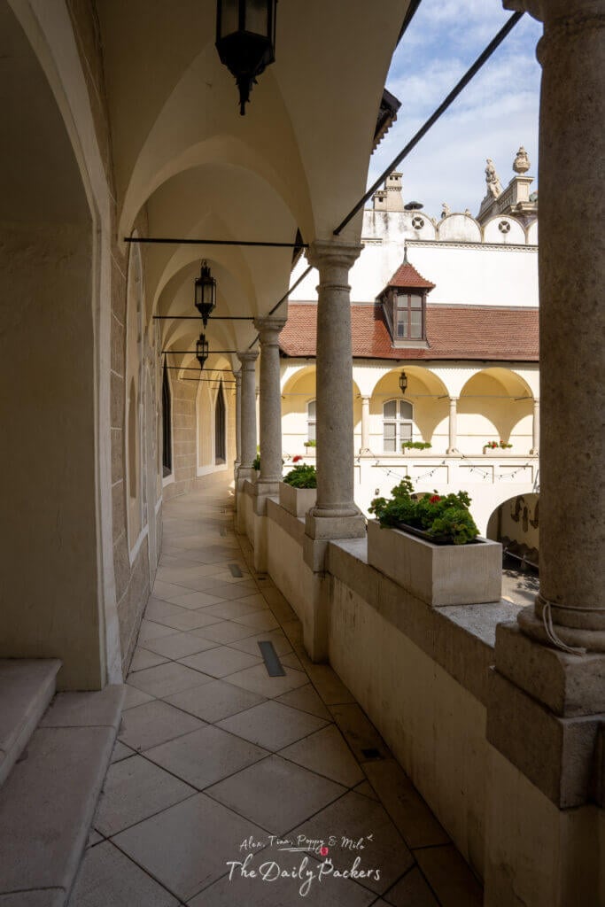 Couloir en pierre avec colonnes voûtées et fleurs en pot à l'intérieur de la cour de l'Hôtel de Ville de la Vieille Ville de Bratislava