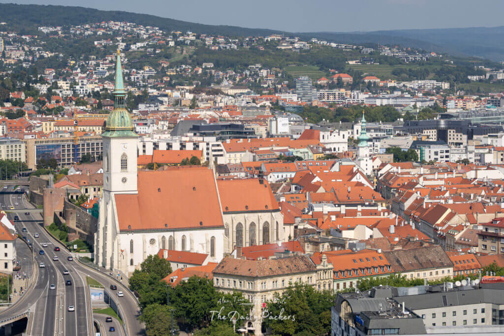 Aerial view of Bratislava old town rooftops with St. Martin’s Cathedral and UFO Tower in the distance.