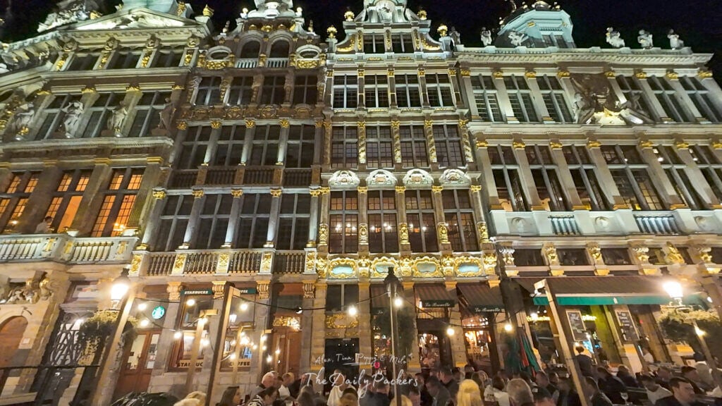 Gros plan sur les maisons des corporations illuminées à la Grand-Place de Bruxelles la nuit avec des détails dorés brillant de mille feux.