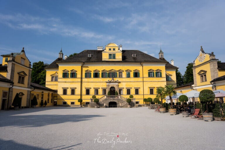 Close-up of the bright yellow facade of Hellbrunn Palace with green shutters and baroque details in Salzburg.
