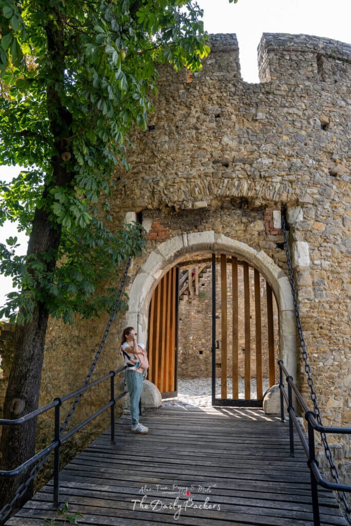 Entrance to the Barbican in Pécs with a wooden bridge and stone gate, a person standing nearby