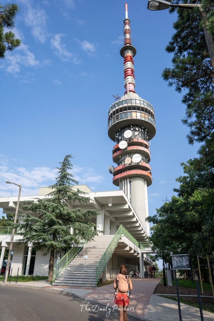Tall TV tower of Pécs with antennas and observation deck, viewed from below with clear blue sky