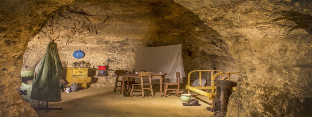 Interior of the Tettye limestone cave museum in Pécs with reconstructed furniture and household items.