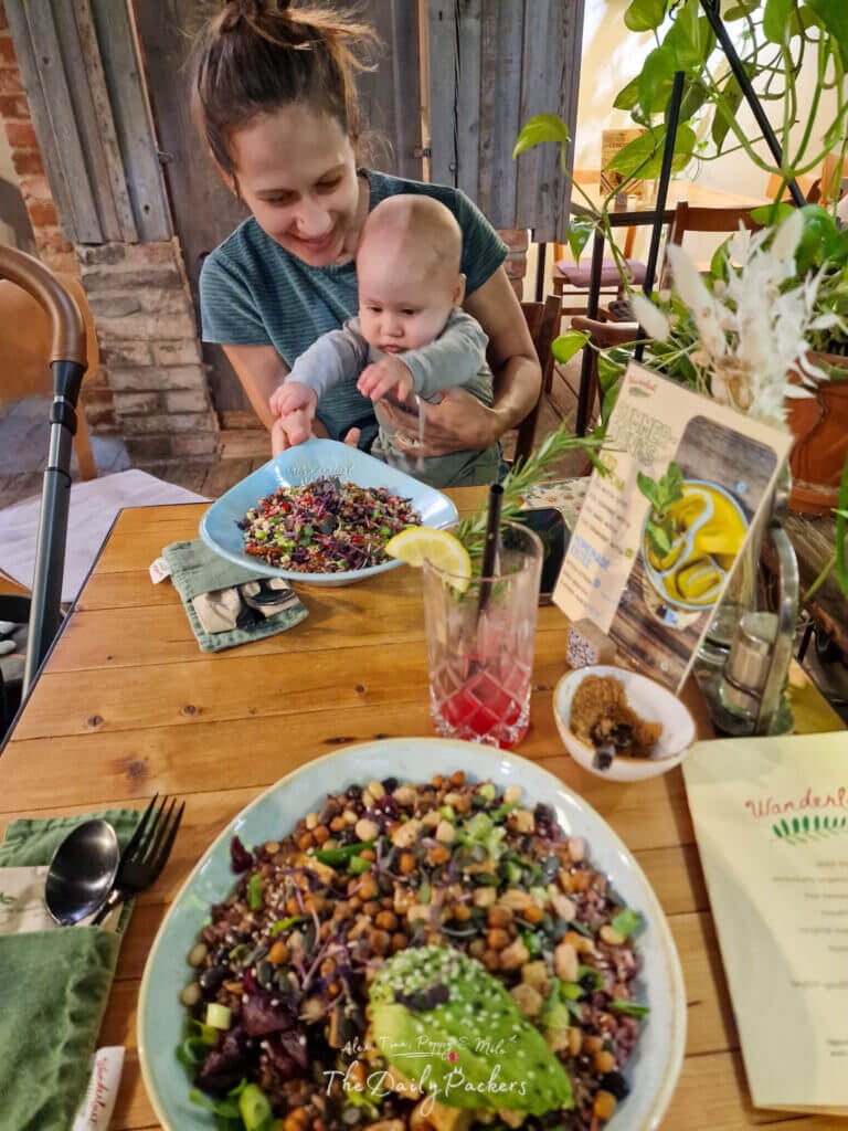 Mother and baby sharing a meal at Wanderlust restaurant in Regensburg with colorful plant-based dishes.