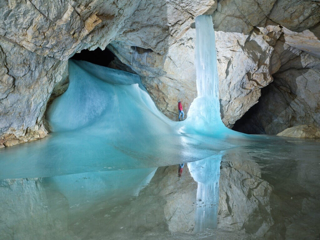 Intérieur de la grotte de glace Eisriesenwelt près de Salzbourg avec des formations gelées massives et une personne debout pour l'échelle