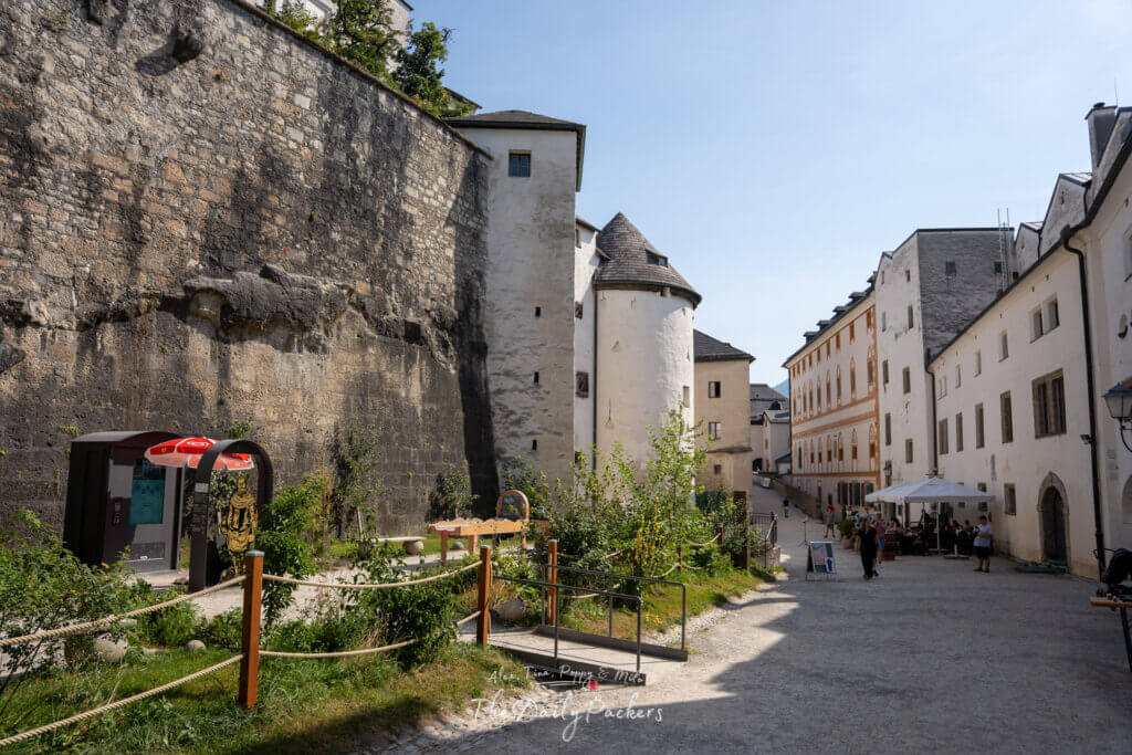Inner courtyard of Hohensalzburg Fortress with outdoor restaurant and visitors exploring the grounds.