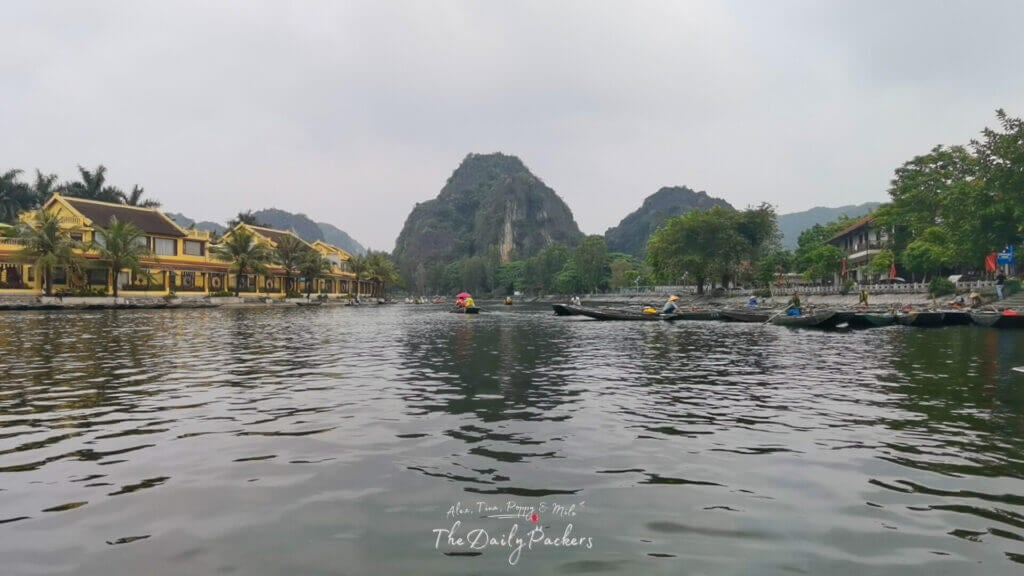 View of Tam Coc town with boats docked near yellow buildings by the riverside.