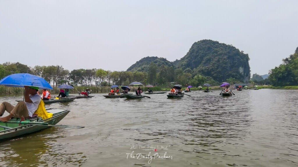 Dozens of boats with tourists and rowers filling the Tam Coc waterway during peak time