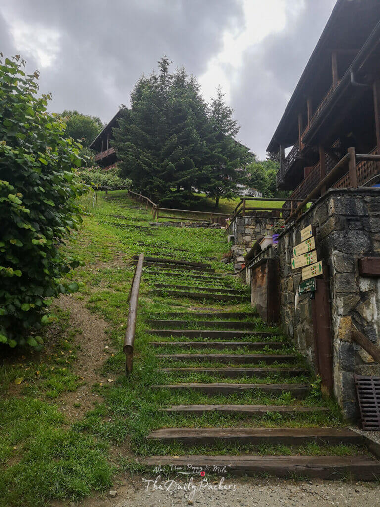 Marches en bois menant en montée devant des chalets aux Houches sous un ciel nuageux.