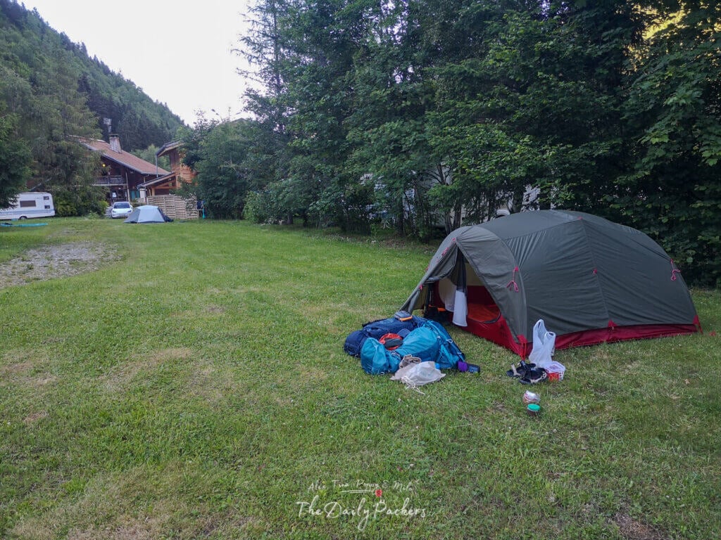 Tente installée sur l'herbe au Camping Le Pontet entourée d'arbres et de montagnes.