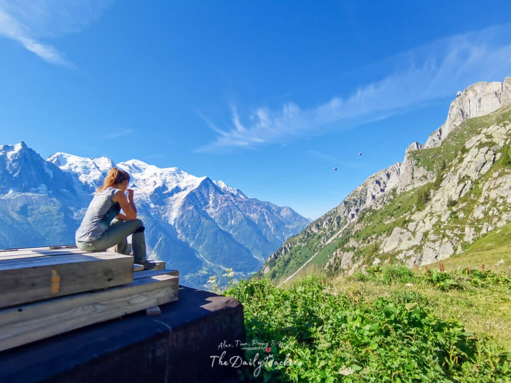 Snack break on stacked planks; gondola line and Mont Blanc in view.