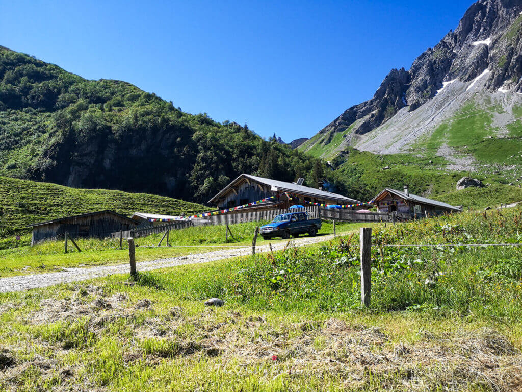 Mountain refuge with Tibetan prayer flags and wooden chalets at the foot of alpine peaks along the Tour du Mont Blanc.