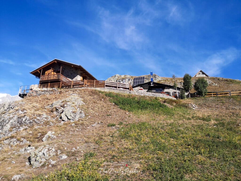 Close-up view of Rifugio Bertone with wooden balconies and solar panels on the hillside.