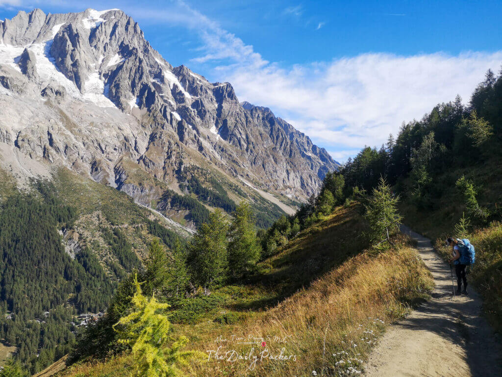 Backpacker walking along a mountain trail overlooking steep rocky peaks and valleys