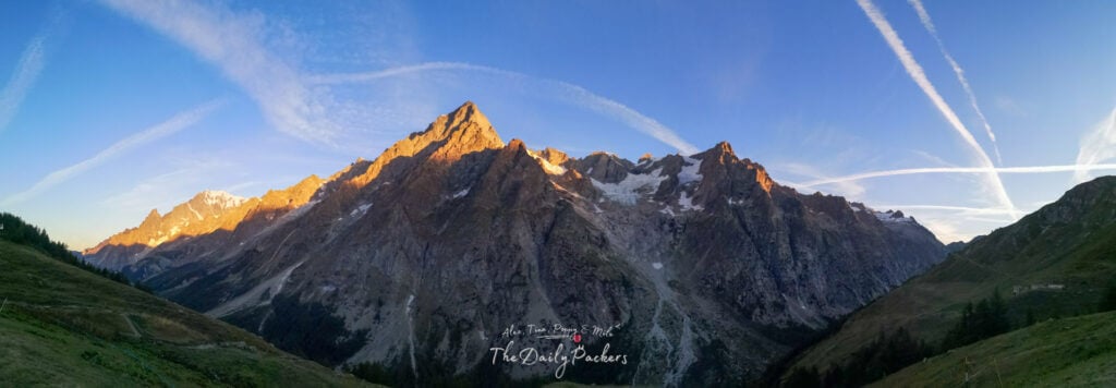 Panoramic view of Mont Blanc massif glowing orange in early morning sunlight.