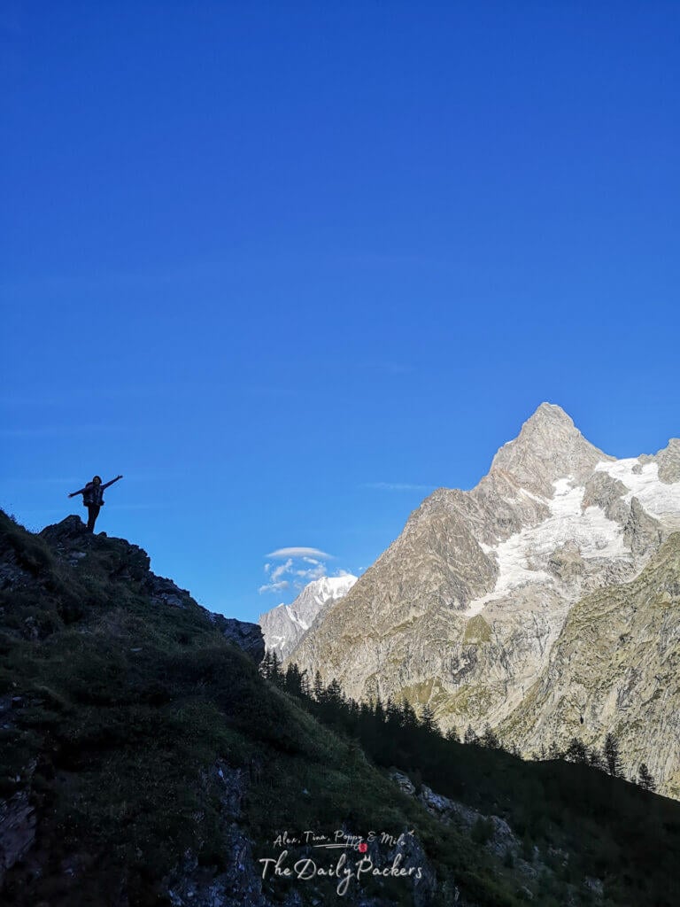 Silhouette of a hiker with arms raised on a ridge overlooking Mont Blanc.