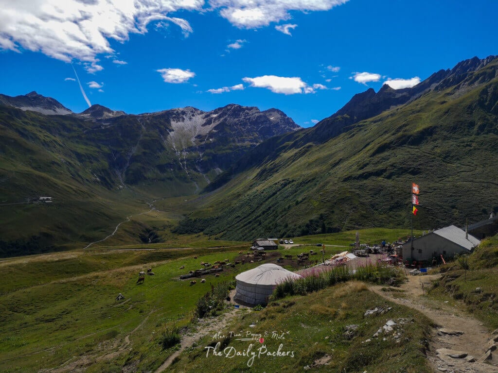 Pastures with cows and mountain views near La Fouly, with a yurt and farm buildings.