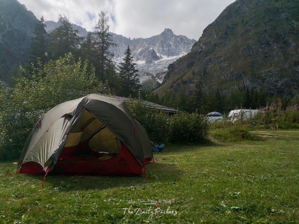 Tent pitched on grassy ground at Camping des Glaciers with mountains behind.