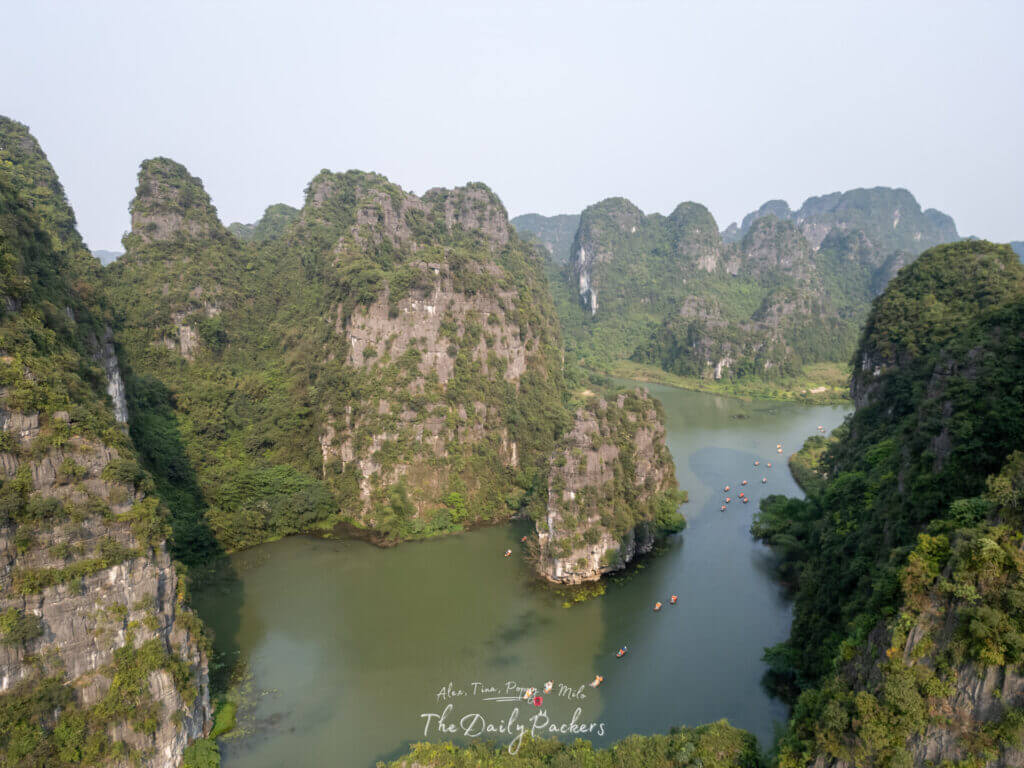 Aerial view of Trang An’s dramatic limestone karsts and winding waterways dotted with small boats in Ninh Binh, Vietnam.