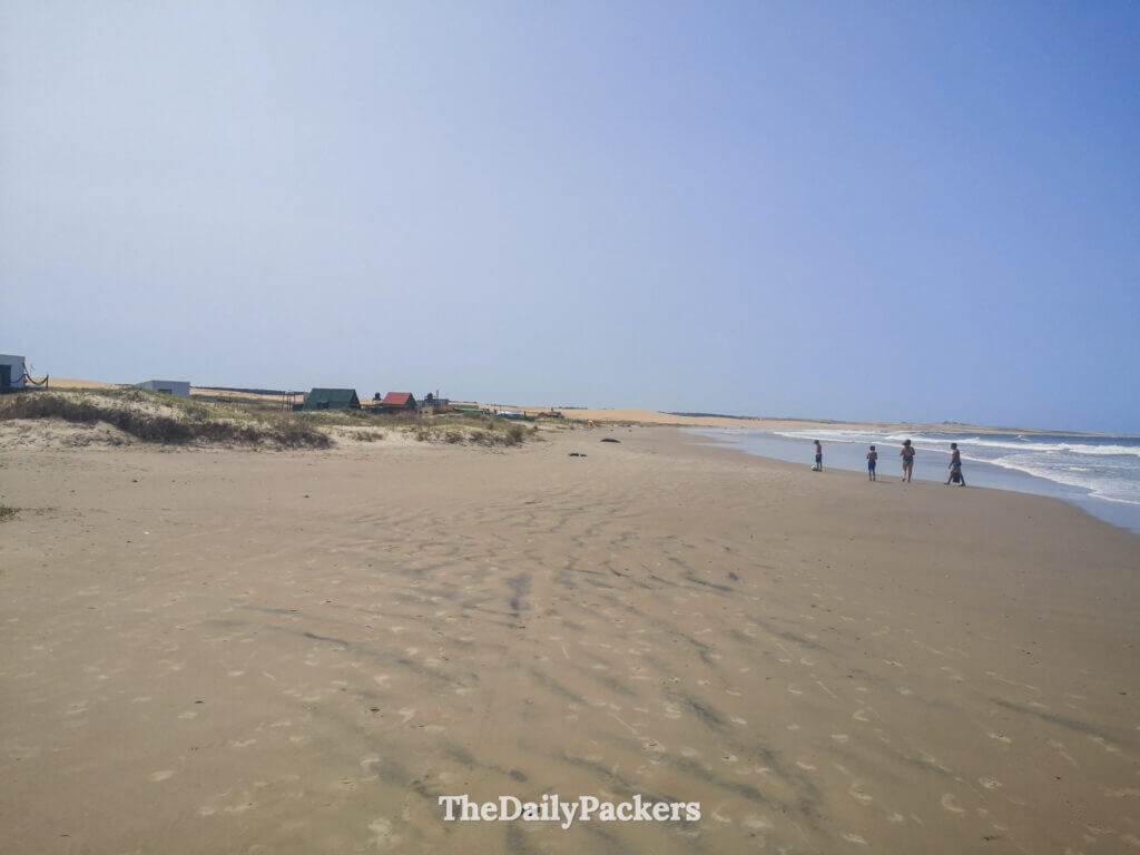 Peaceful sandy beach in Cabo Polonio with a few people walking along the water.